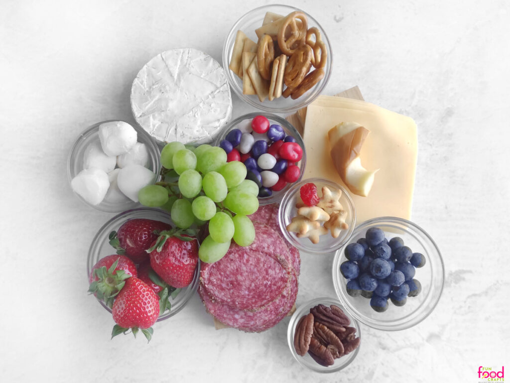 Ingredients like blueberries, strawberries, and cheese to make Uncle Sam Charcuterie Board in small glass bowls