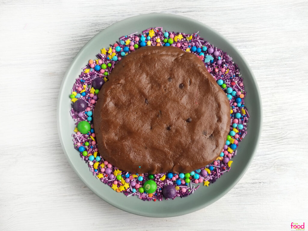 Chocolate cookie dough shaped into a large round circle on a plate if switches