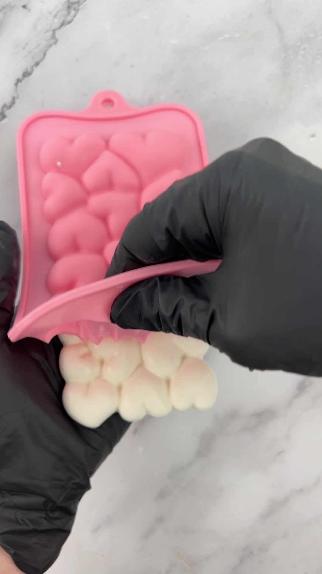 Removing a set white candy bar from a pink silicone heart mold