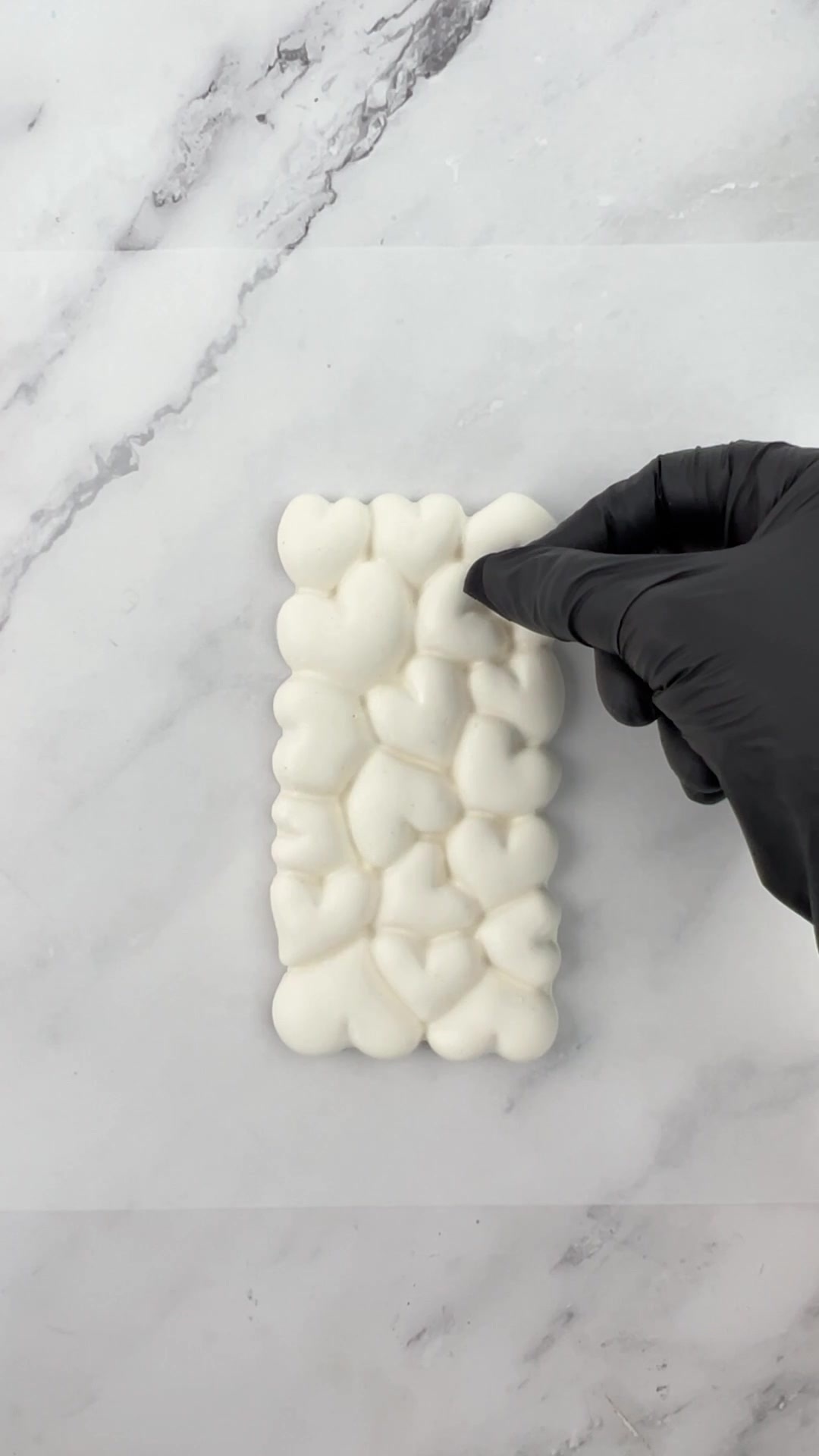 Adding black fondant ears to the top of a heart-textured candy bar