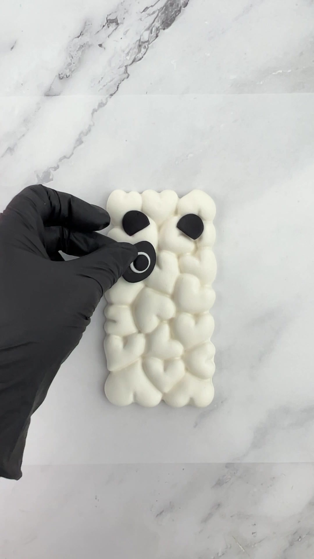 Positioning black-and-white fondant eyes on a homemade panda treat