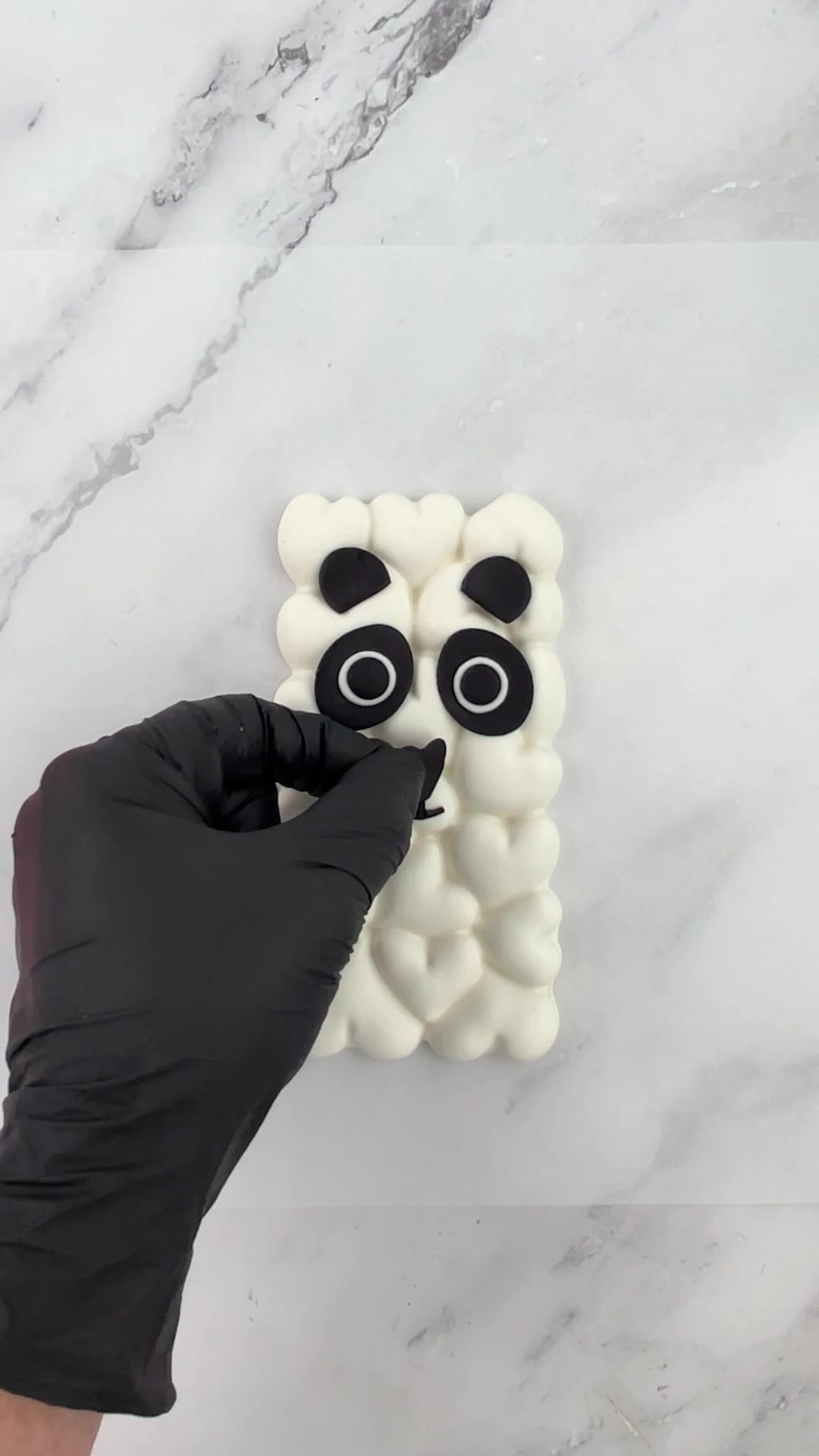 Attaching the black fondant nose and mouth to a panda chocolate bar